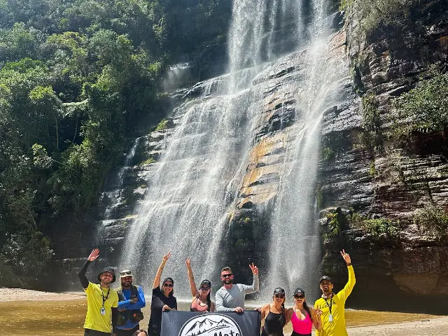 Grupo comemorando em frente a uma cachoeira