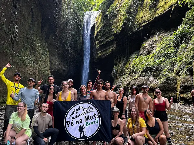 Grupo no fundo de um cânion com cachoeira