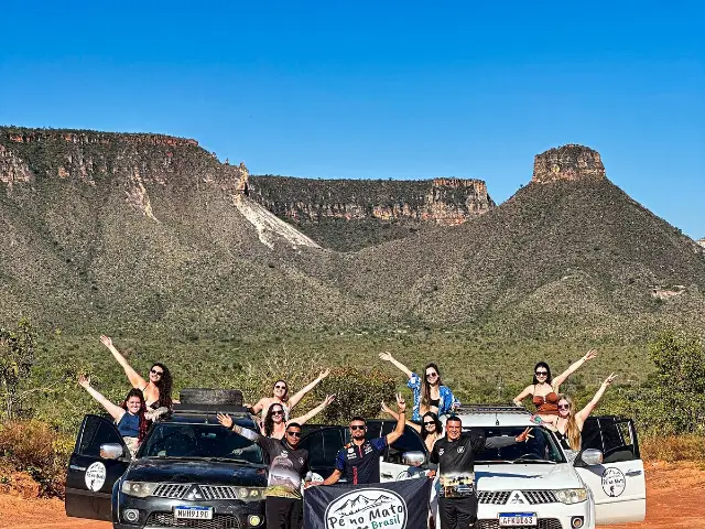 Grupo com os braços para cima diante da serra
